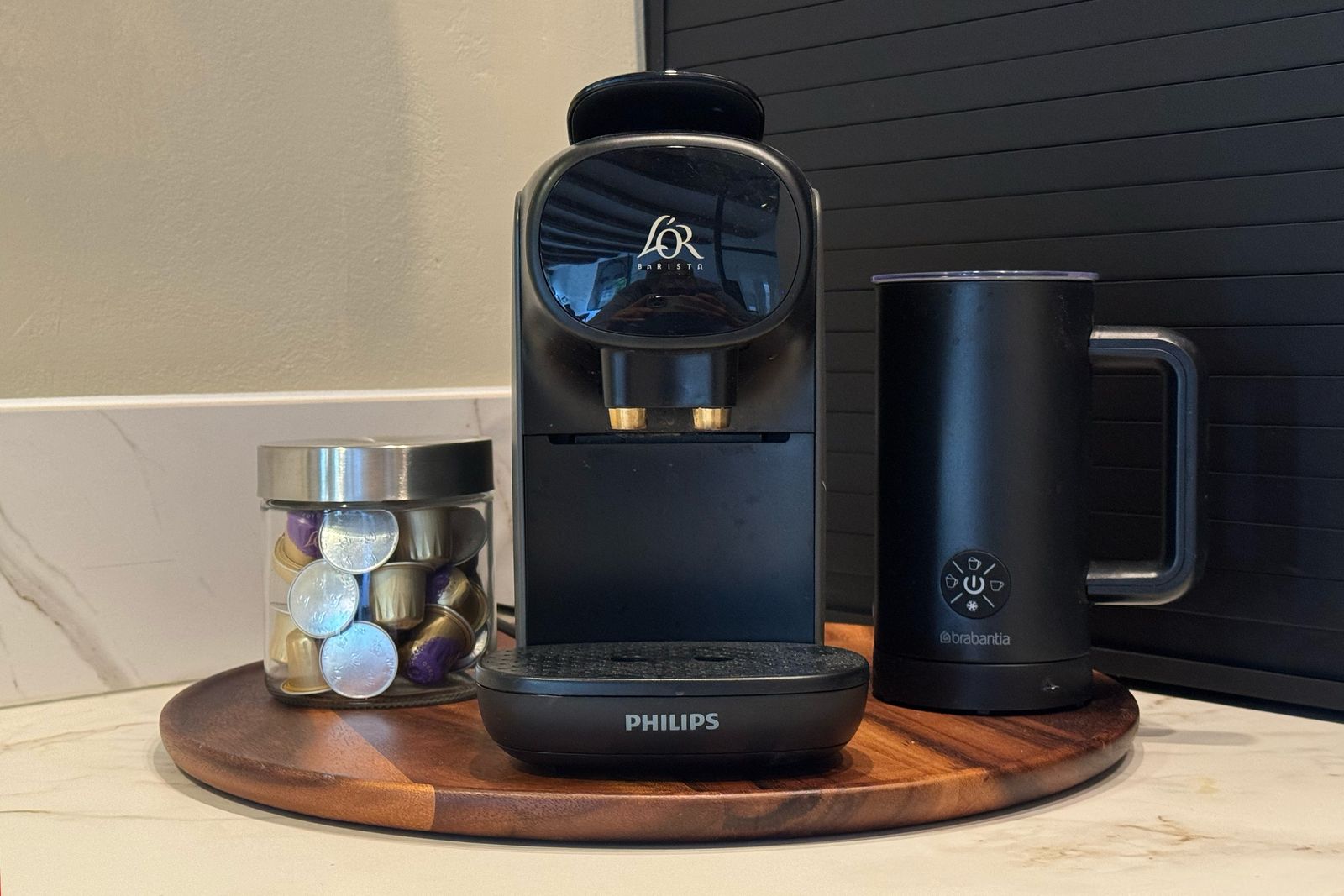 The coffee nook at Waal with an L'OR Barista capsule machine, a milk frother and a jar of capsules on a wooden board