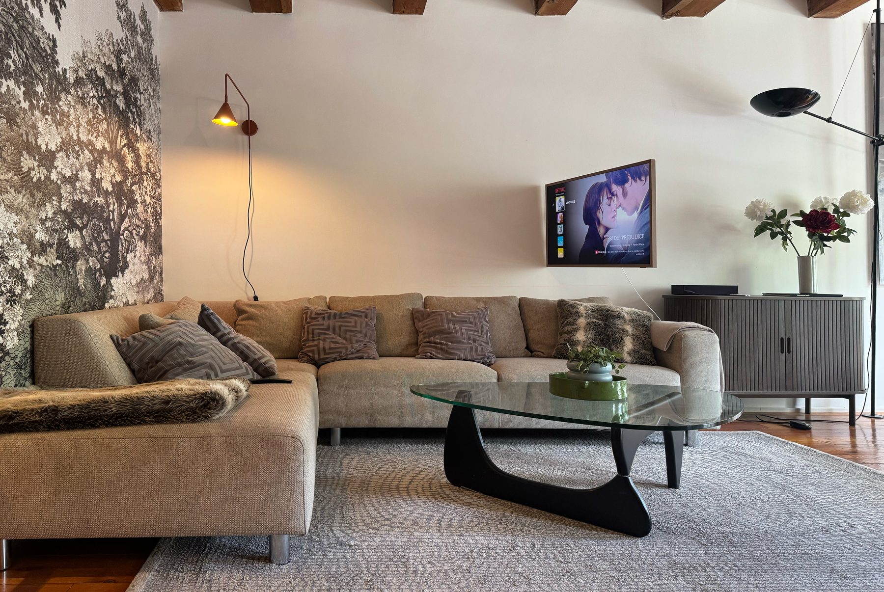 Lounge at Waal with a deep sectional sofa, glass coffee table and the wall-mounted Frame television beneath an exposed beam