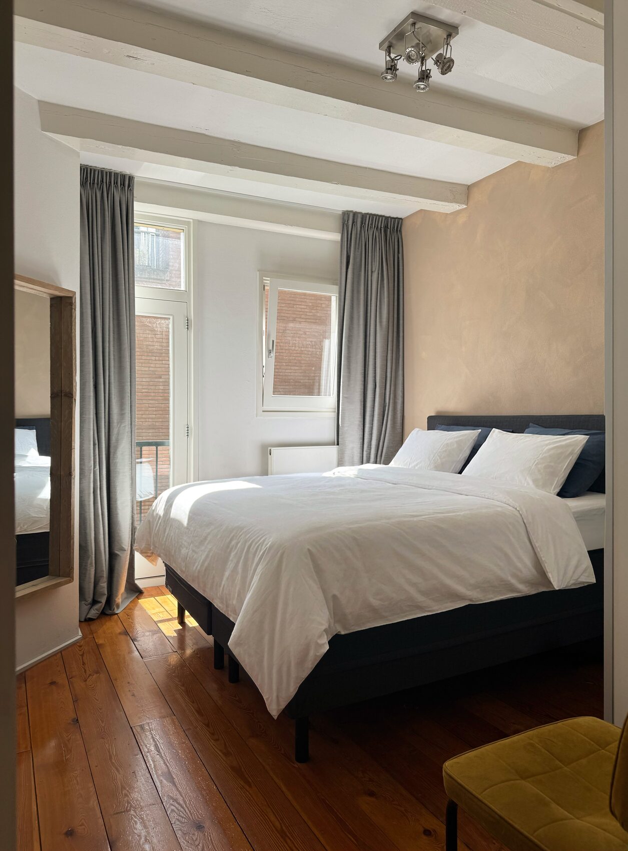 Master bedroom at Waal with a king bed in white percale linen, grey curtains and a doorway to a private French balcony