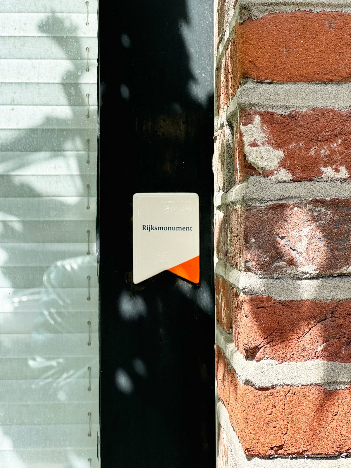 The Dutch Rijksmonument plaque mounted on the black door frame of Waal beside the historic red brick facade